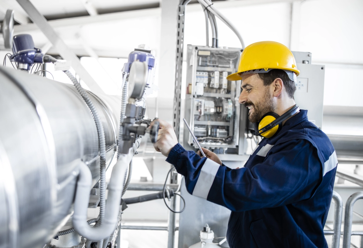 Engineer adjusting machinery in industrial setting.
