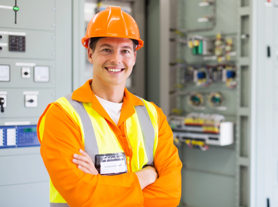 Smiling engineer in safety gear, control room.